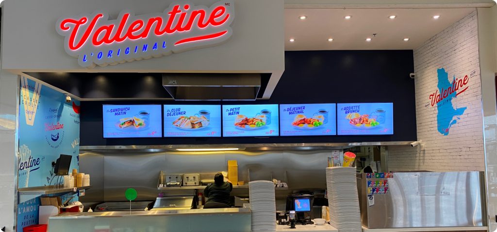 Valentine restaurant interior with menu screens and food prep area.