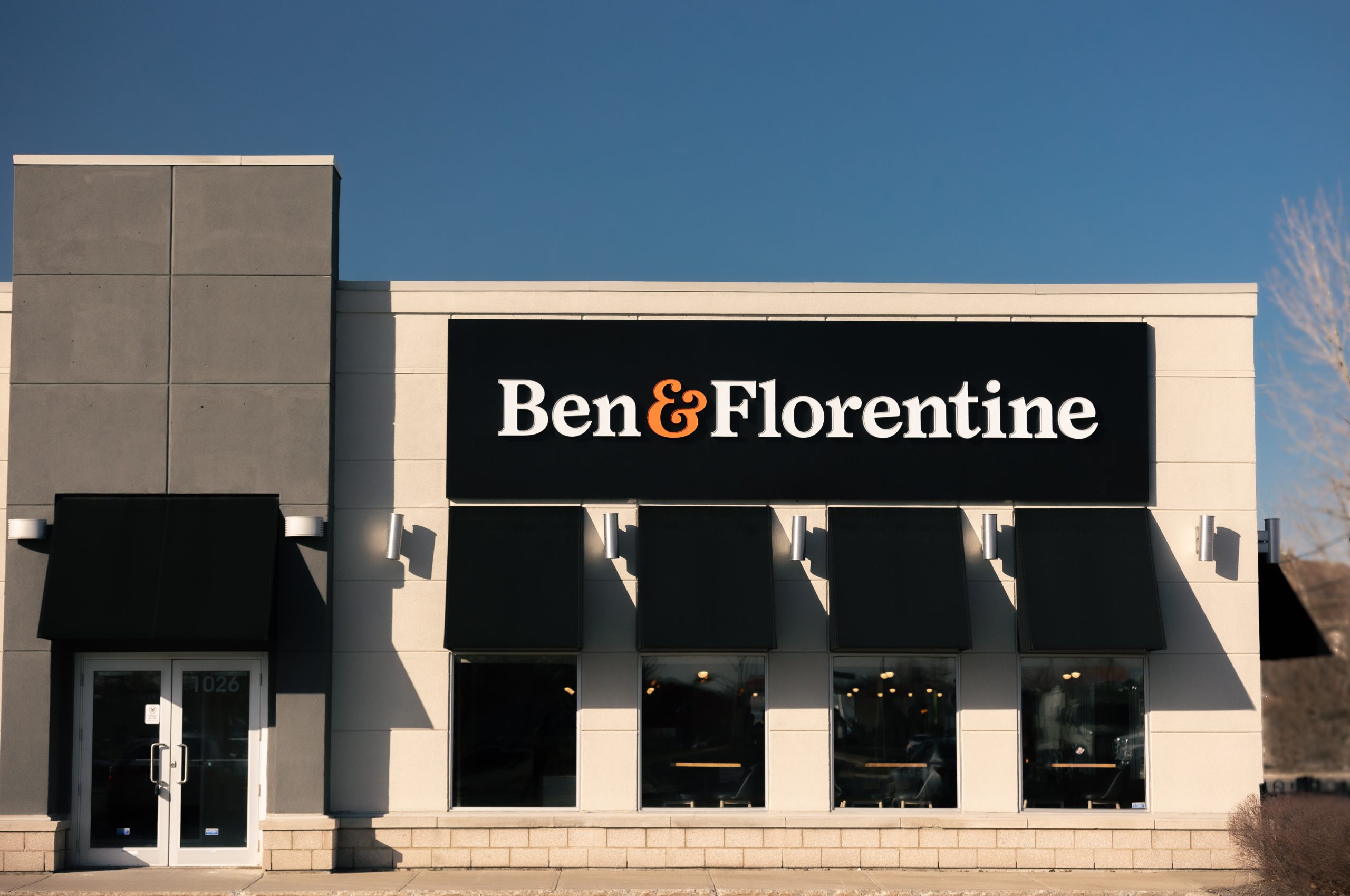 Ben & Florentine restaurant exterior with black awnings and clear blue sky.