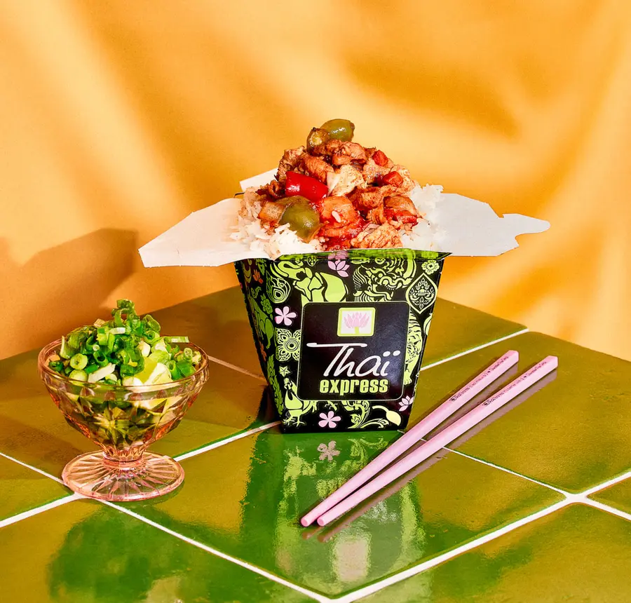 A delicious Thai meal from Thaï Express served with rice, vegetables, and a side of fresh herbs, ready to enjoy.