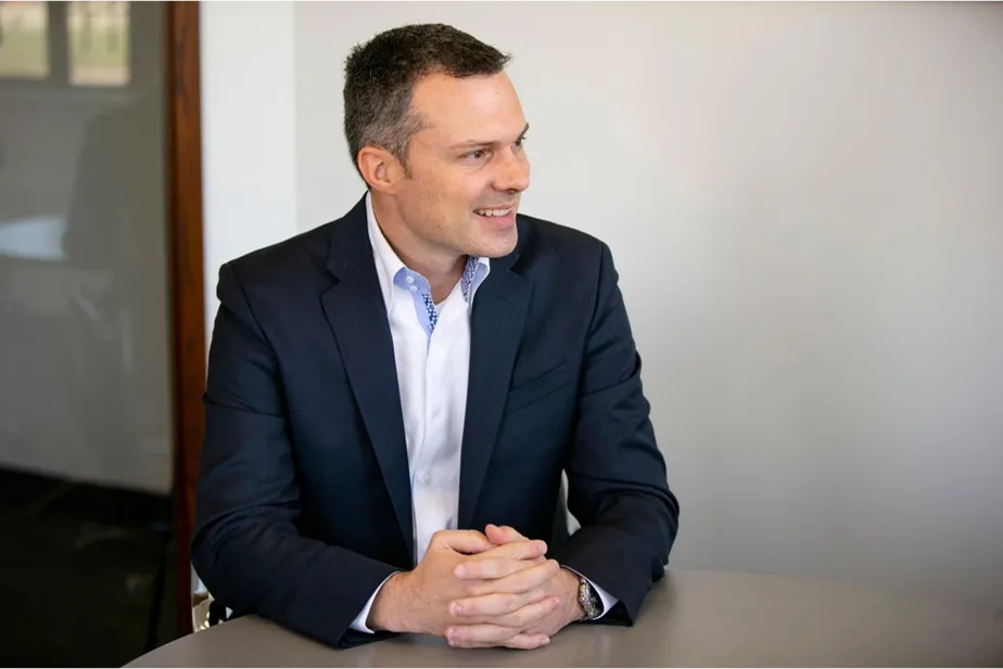 Eric Lefebvre, CEO of MTY Group, offering expert advice on selecting the right franchise, with a focus on achieving business goals. The image shows him in a thoughtful pose at a meeting table. | The Strategy Behind Selling Happiness with a Thriving Franchise: A Conversation with MTY's CEO Blog