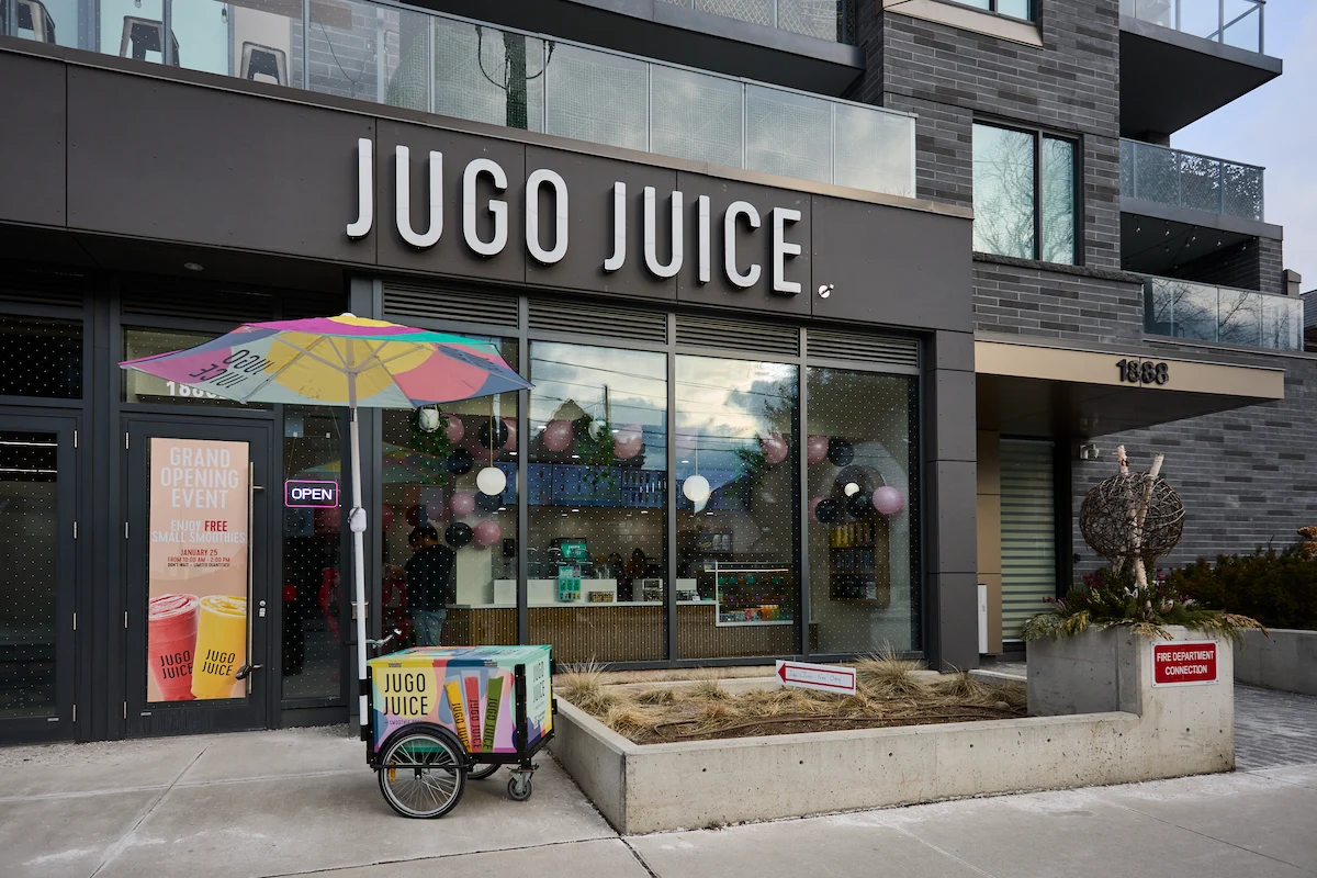 Jugo Juice storefront with colourful umbrella, balloons, and branded signage, showcasing a vibrant franchise opportunity in Canada.