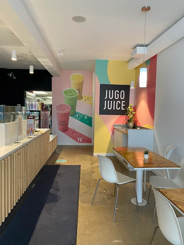 Modern Jugo Juice interior featuring branded wall graphics, menu boards, and cozy seating areas.